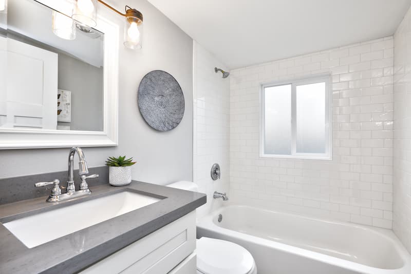 Modern bathroom interior with white vanity topped with gray countertop.